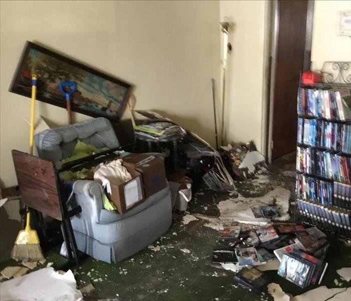 Living room with wet carpet around a gray chair with items scattered around