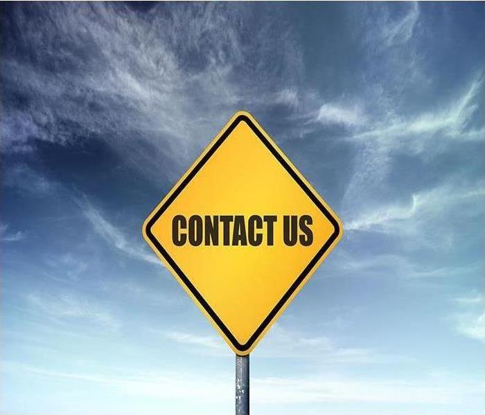 Yellow 'contact us' sign against blue sky