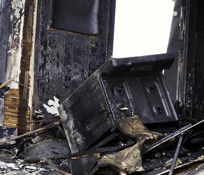 A kitchen with an oven turned over with fire and soot damage.