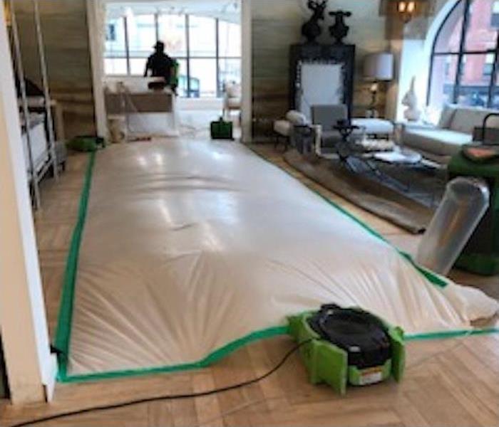drying equipment and tarp over a water damaged hardwood floor