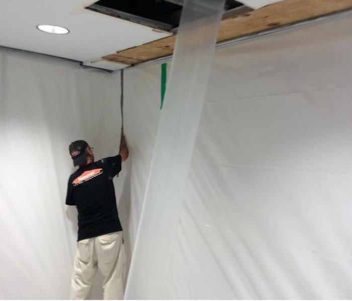 employee setting up a containment barrier in a mold damaged home